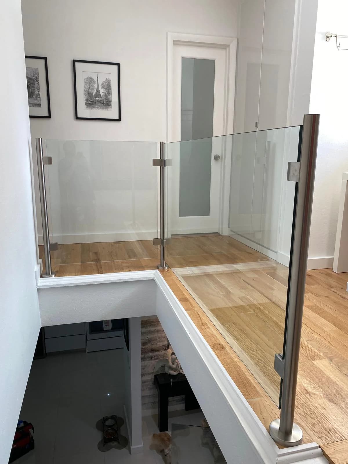 Frameless glass guard panels on an interior landing held by stainless steel clamps