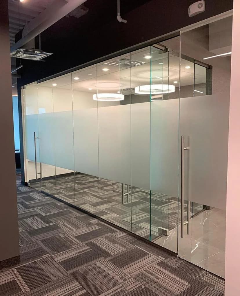 Glass office partition with a frosted privacy band and frameless glass door