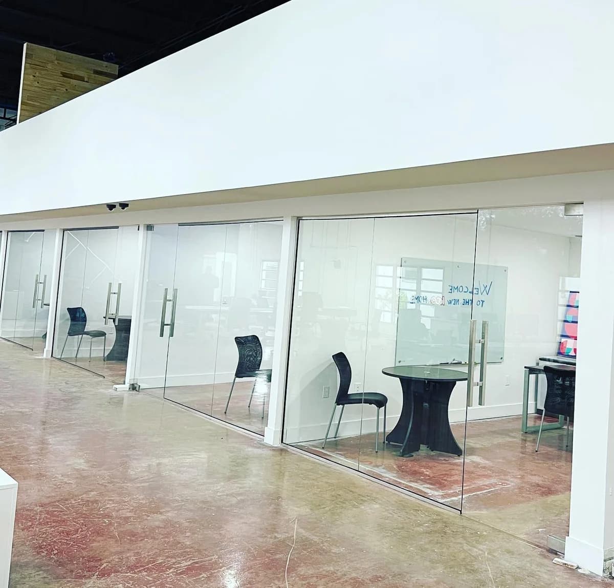 Frameless glass partition enclosing a meeting room with modern furniture in a South Florida office