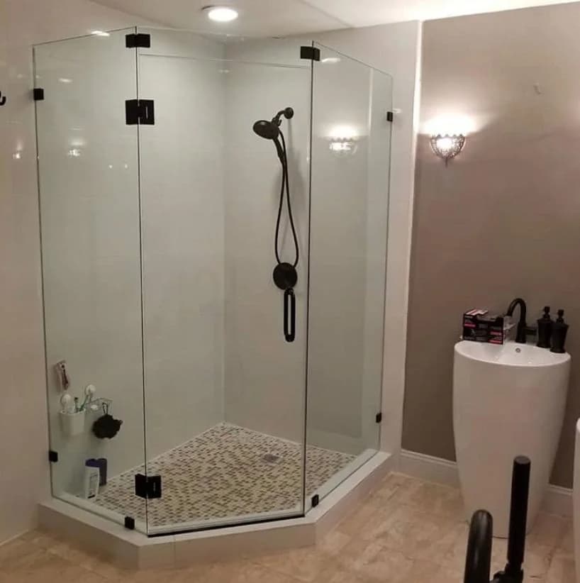Clear frameless shower glass and chrome handle in a bright white bathroom