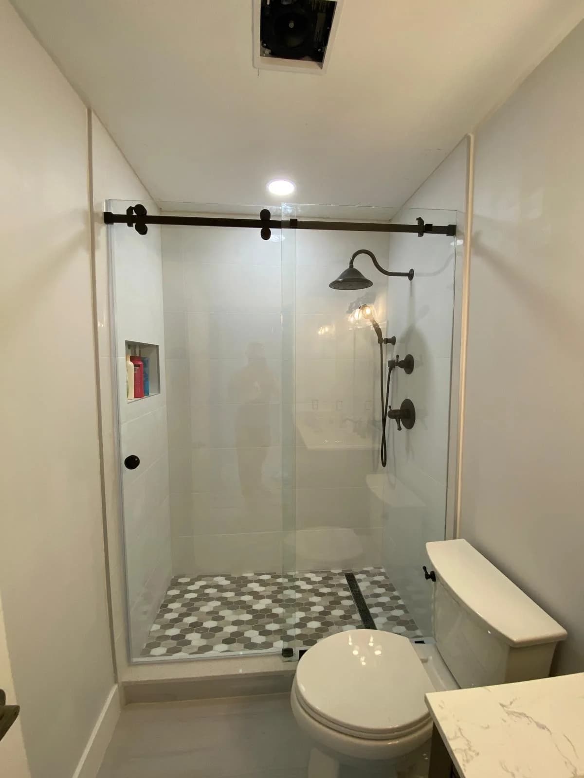 Frameless sliding glass shower door with matte black barn-style track in a Miami bathroom