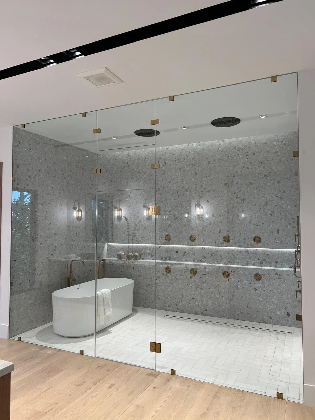 Frameless shower enclosure with ultra-clear glass and brushed brass hardware in a South Florida bathroom